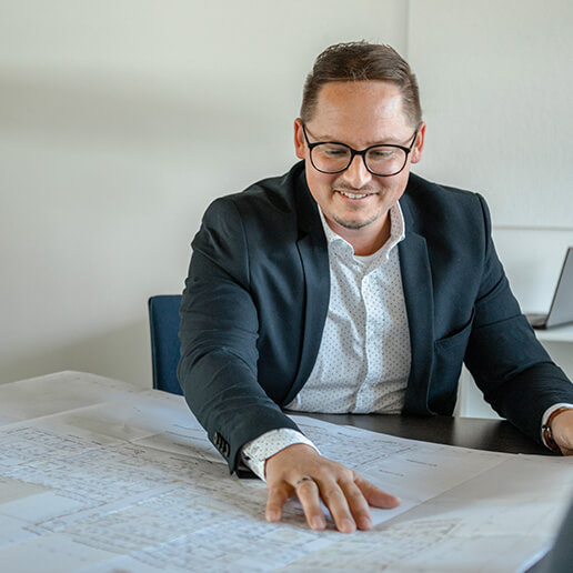 Bauzeichner Stefan Bär betrachtet einen Bauplan im Büro von Kling Consult