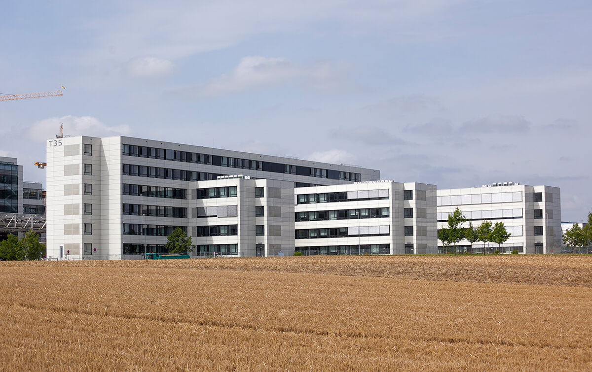 Außenansicht Bürogebäude T35 Audi Ingolstadt - Moderne Wohngebäude mit weisser Fassade, die sich hinter einem Ackerfeld befinden