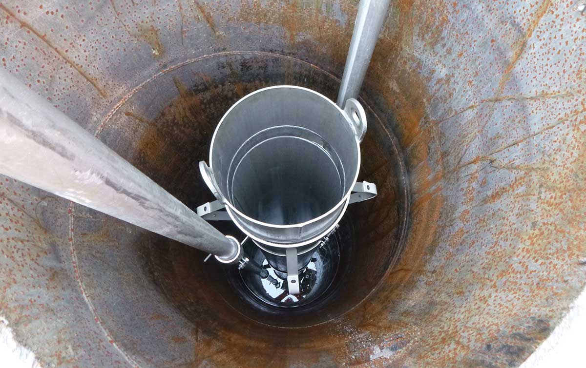 Blick in einen Brunnen mit einer Metalleimerzentrierung, die hinabgelassen wird