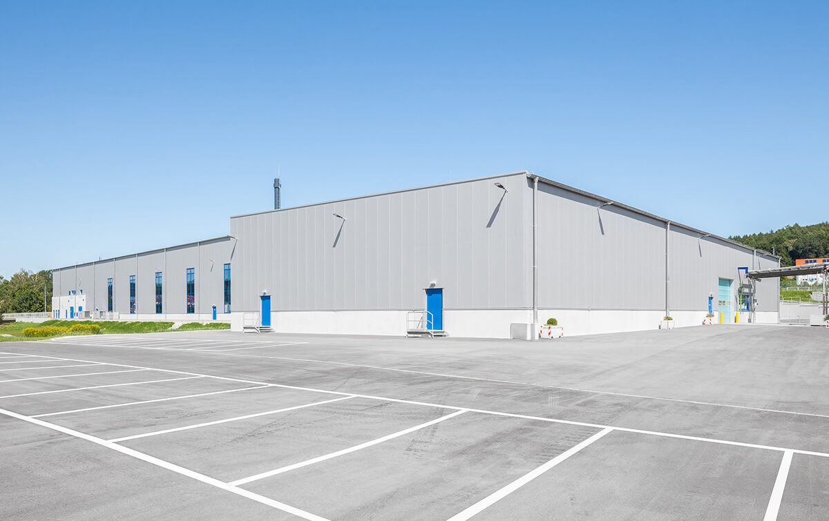 Außenansicht der Produktions- und Lagerhalle mit Parkplatz der Indorama Ventures Mobility Krumbach GmbH & Co. KG