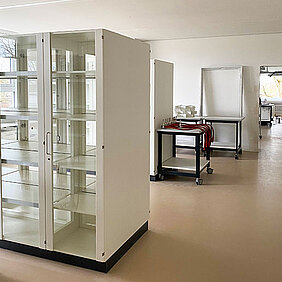 Leerer Laborraum/Chemiesaal der Wilhelm-Leibl-Realschule Bad Aibling mit weißen Regalen und Tischen, einem mobilen Wagen.